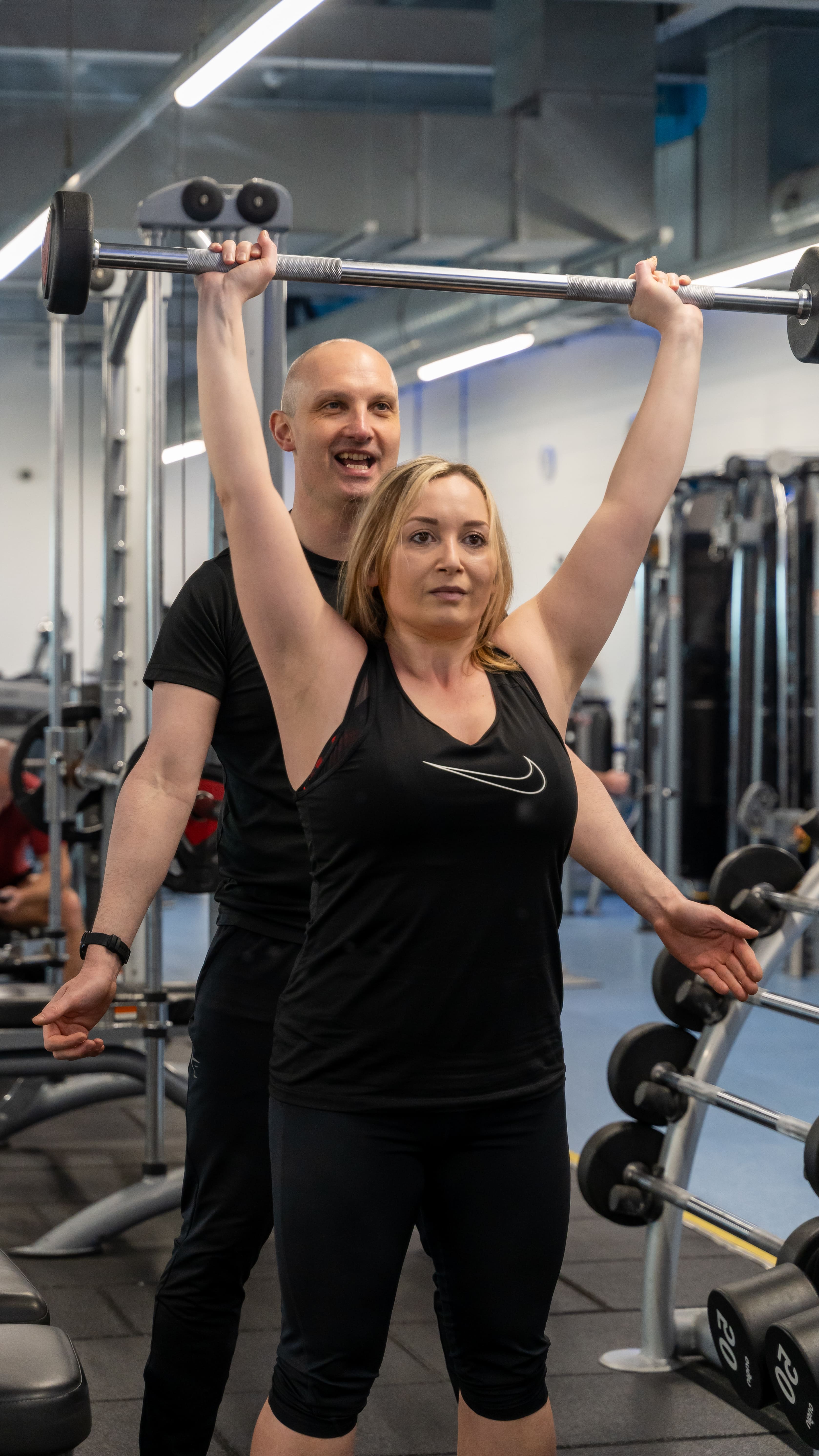 Personal trainer in Norwich coaching a client on overhead barbell press technique